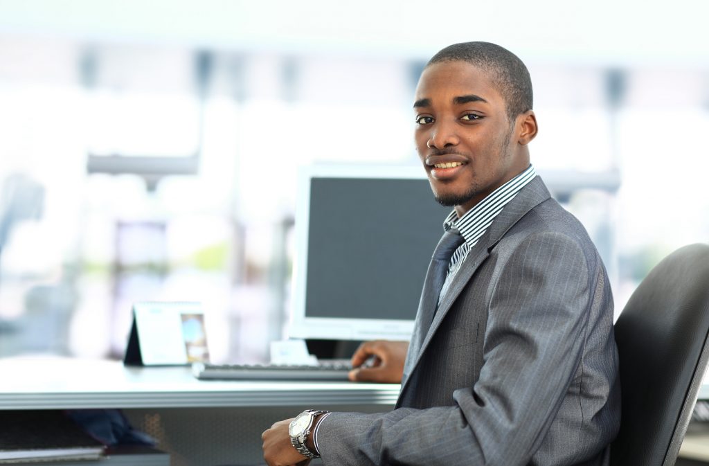 Portrait of a happy African American entrepreneur displaying computer laptop in office